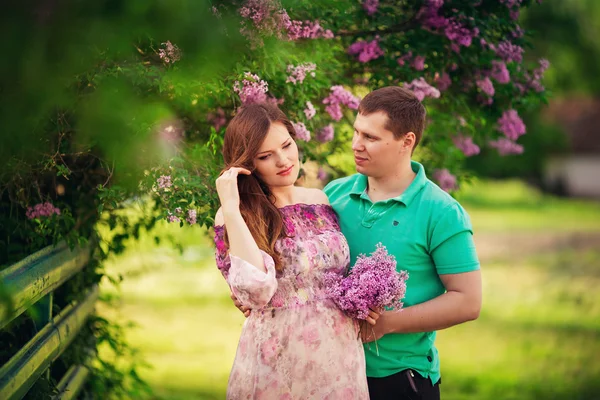 Pregnant woman with her husband in garden — Stock Photo, Image