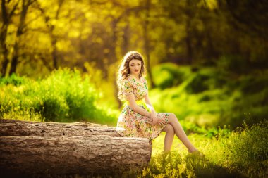 bir orman içinde ahşap üzerinde oturan kadın