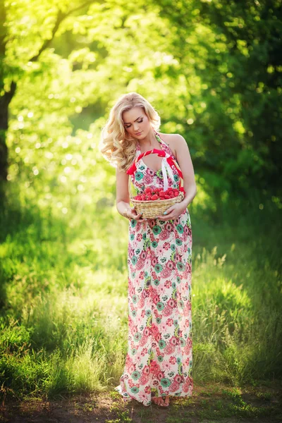 Vrouw met mandje van aardbei in tuin — Stockfoto