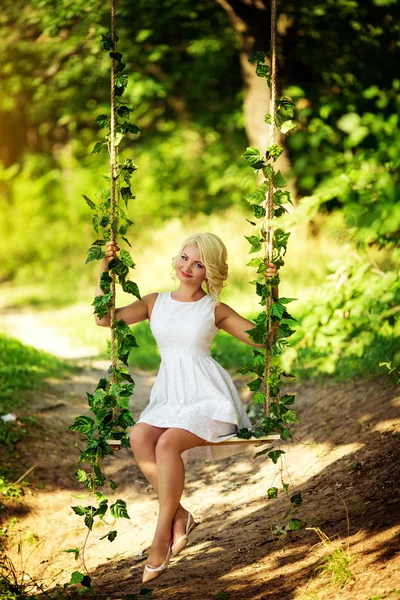 Mulher sentada em um balanço no jardim — Fotografia de Stock