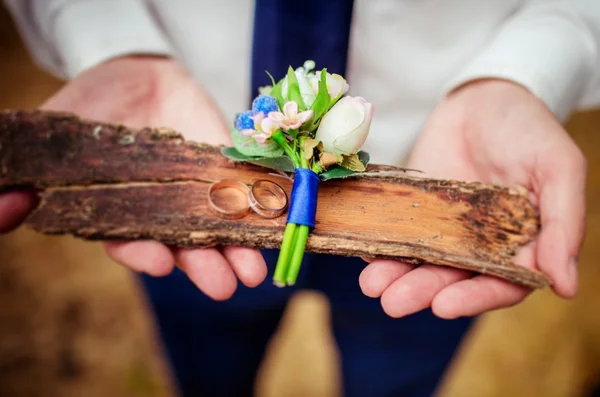 Anillos de boda y boutonniere en manos del novio — Foto de Stock