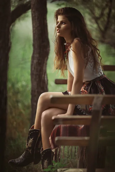 Kvinna i modekläder satt på en bänk — Stockfoto