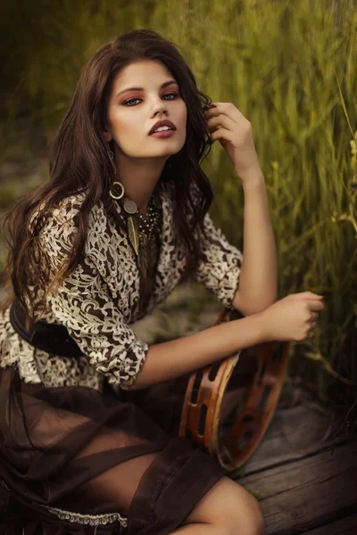 Mujer elegante sentada en la orilla del río — Foto de Stock