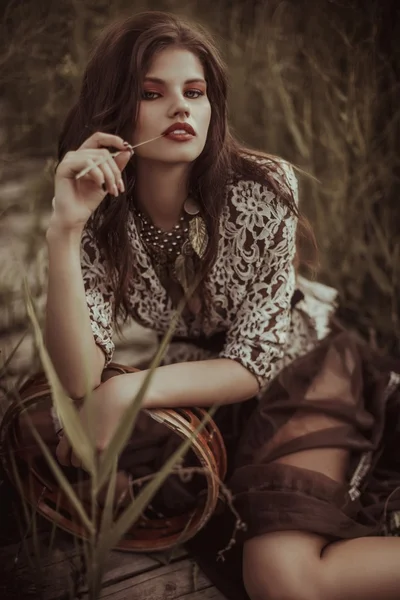 Mujer elegante sentada en la orilla del río — Foto de Stock