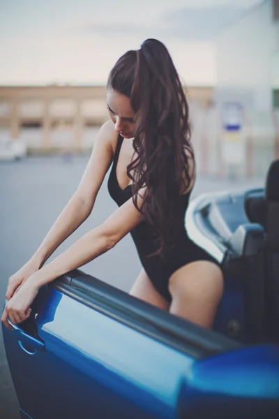 Mooie vrouw poseren in de buurt van blauwe auto — Stockfoto