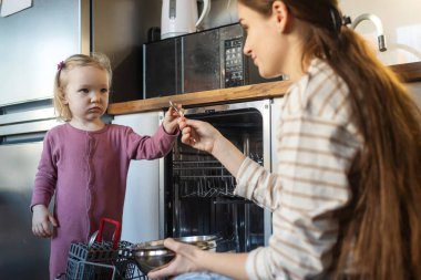 Bulaşık makinesini paketlemek onun en sevdiği iştir. Küçük tatlı bir kız ve annesinin evde bulaşık makinesini doldururken çekilmiş..
