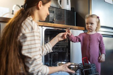Bulaşık makinesini paketlemek onun en sevdiği iştir. Küçük tatlı bir kız ve annesinin evde bulaşık makinesini doldururken çekilmiş..
