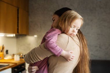 Happy single mother doing her daughter's hair while having breakfast. Woman combs the hair of a little girl. The concept of morning routine, single parenthood and preparation for school.