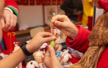 Çin Yeni Yıl mum atölyesi - geleneksel bayram sembolleri ve kırmızı kağıttan Çince karakterler yaratmak. Kültürel sanatlar etkinliği Ay Yeni Yıl Geleneklerini kutluyor