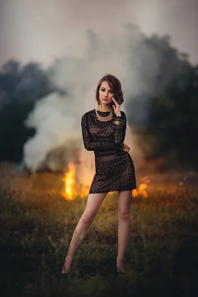 Girl stands on a background of burning fire — Stock Photo, Image