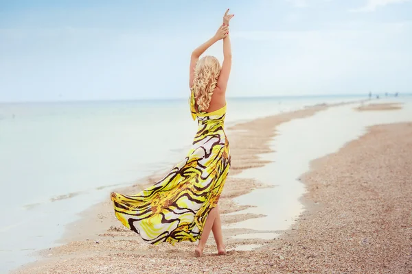 Fille en robe jaune sur un bord de mer — Photo
