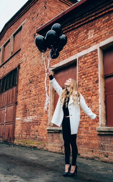 Meisje in trendy kleding met zwarte ballonnen — Stockfoto