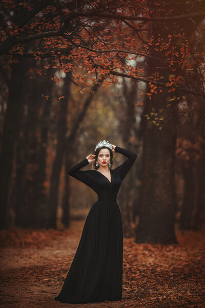 Beautiful model woman with professional make up wearing crown posing at autumn park