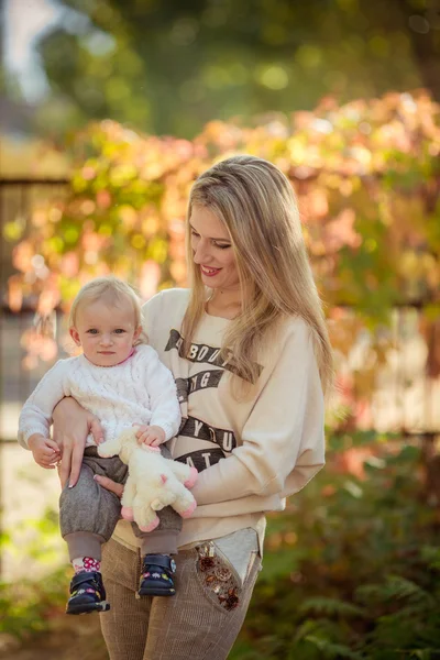 Mamma med barn flicka i höst trädgård — Stockfoto