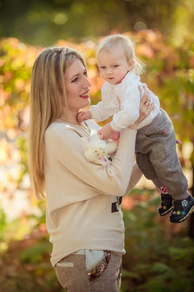 Mamma med barn flicka i höst trädgård — Stockfoto