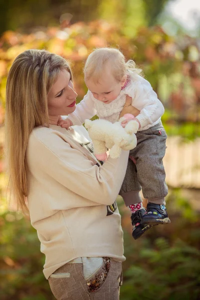 Mamma med barn flicka i höst trädgård — Stockfoto