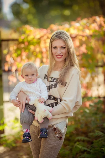 Mamma med barn flicka i höst trädgård — Stockfoto