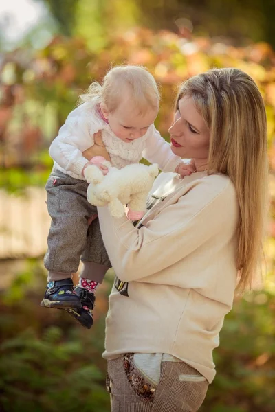 Mamma med barn flicka i höst trädgård — Stockfoto