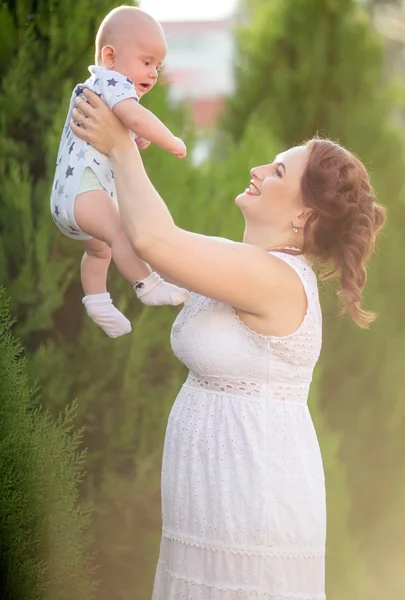 Moeder gooit up babyjongen in de lucht — Stockfoto