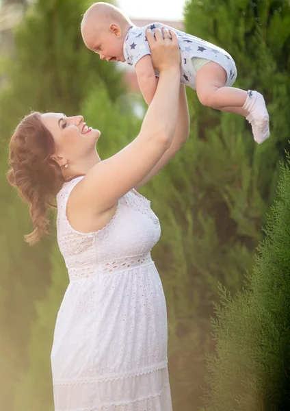 Mother throws up baby boy in the air — Stock Photo, Image