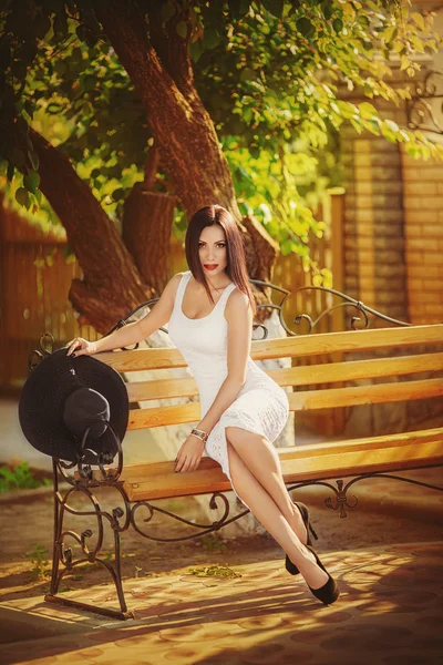 Beautiful young woman sitting on a bench — Stock Photo, Image