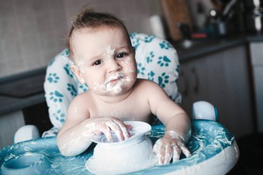 İlk kez tatlı yiyen sevimli, dağınık bir bebeğin portresi..