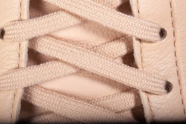 Bej renkli spor ayakkabıların üzerindeki bej bağcıkların yakın plan çekimi günlük giyim için.