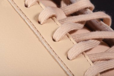 Bej renkli spor ayakkabıların üzerindeki bej bağcıkların yakın plan çekimi günlük giyim için.