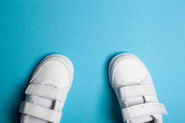 Childs nowe białe buty sportowe lub trampki na jasnoniebieskim pastelowym tle. — Zdjęcie stockowe