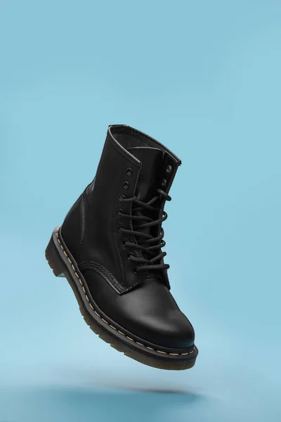 Mavi arka planda siyah çizmeler var. Moda ayakkabıları hala hayat. Klasik unisex siyah dantelli moda savaş botu. Metin için kopyalama alanı olan yükseltme önyükleme görünümünü kapat