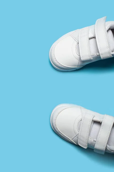 Παιδικά καινούργια λευκά αθλητικά παπούτσια ή sneakers στο γαλάζιο παστέλ φόντο. — Φωτογραφία Αρχείου