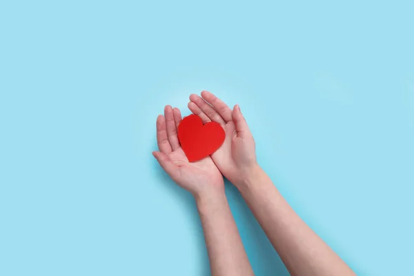 Manos de mujer sosteniendo el corazón en el fondo azul. dar amor filantropía. donar ayuda calidez y cuidar. día de San Valentín —  Fotos de Stock