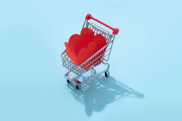 Carro de compras lleno de corazones para el Día de San Valentín sobre fondo azul —  Fotos de Stock