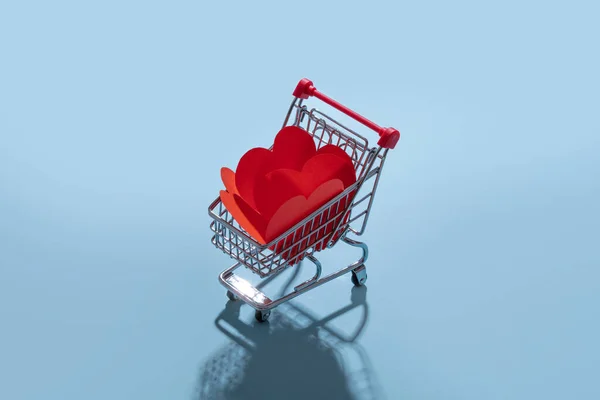 Carro de compras lleno de corazones para el Día de San Valentín sobre fondo azul —  Fotos de Stock