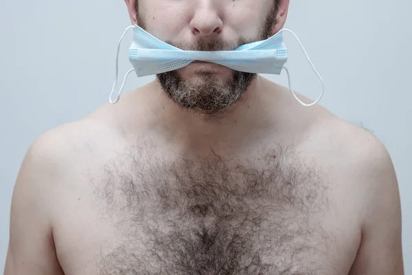 Злой бородатый мужчина держит защитную маску во рту. — стоковое фото