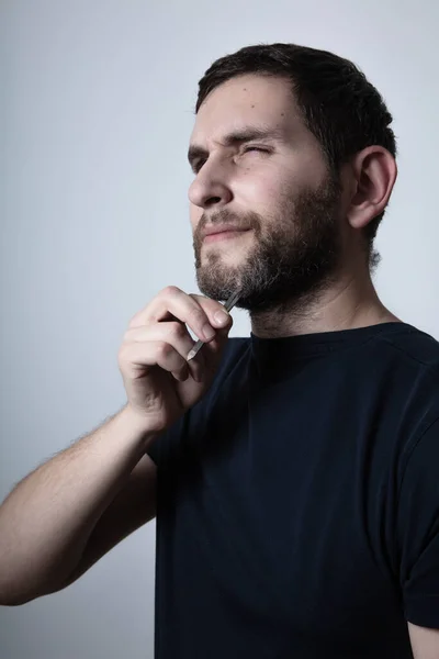 Hombre con problema de barba gris arrancando pelo con pinzas de barba —  Fotos de Stock
