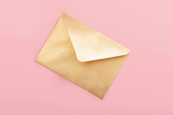 Envelope de papel dourado isolado sobre fundo rosa — Fotografia de Stock