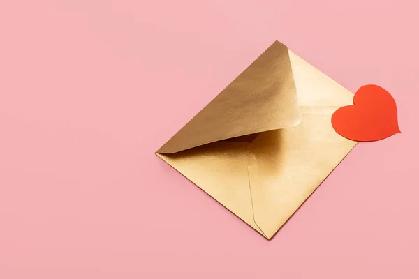 Золотий паперовий конверт з червоним серцем ізольовано на рожевому фоні — стокове фото