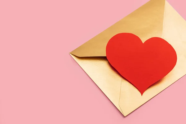 Envelope de papel dourado com coração vermelho isolado em fundo rosa — Fotografia de Stock