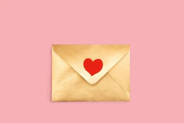 Золотий паперовий конверт з червоним серцем ізольовано на рожевому фоні — стокове фото