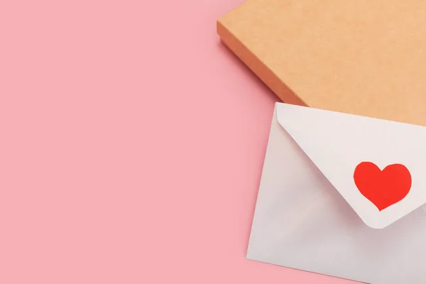 분홍색 배경에 고립 된 선물 상자에 빨간 하트가 달려 있는 진주조개 종이 봉투 — 스톡 사진