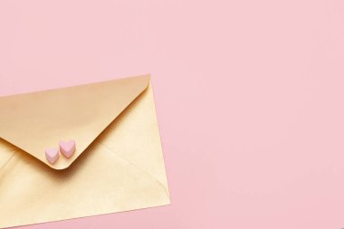 Pembe arka planda marşmelovdan iki kalp izole edilmiş altın kağıt zarf.