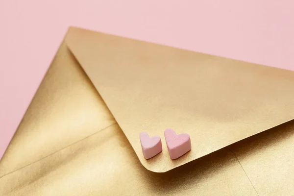 गोल्डन पेपर लिफाफा गुलाबी पृष्ठभूमि पर अलग मार्शमलो से दो दिल के साथ — स्टॉक फ़ोटो, इमेज