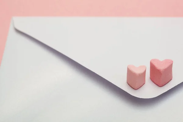 Envelope de artesanato de papel madrepérola leve com dois corações de marshmallow isolado em fundo rosa — Fotografia de Stock