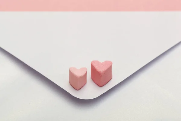 Envelope de artesanato de papel madrepérola leve com dois corações de marshmallow isolado em fundo rosa — Fotografia de Stock