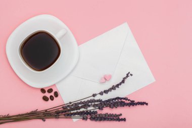 İçinde lokum ve kuru lavantadan yapılmış iki kalp ve pembe arka planda kavrulmuş kahve çekirdekli beyaz kahve bardağı olan boş bir zarf. Aşk mektupları yazıp yolluyorum.