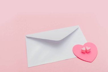 Pembe arka planda kağıt kalpli kapalı inci kokulu zarf.