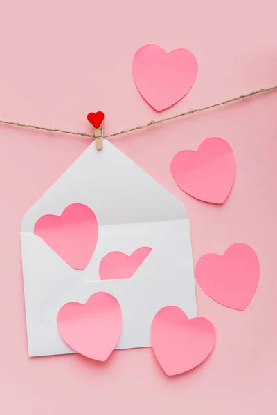 open mother-of-pearl envelope hanging on a rope on clothespins with red hearts