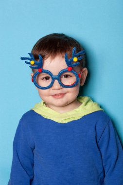 Büyük çocuk gözlüklü komik küçük çocuk. Stüdyoda, mavi arkaplanda.