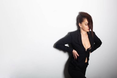 Çok çekici bir genç kız modeli beyaz arka planda duruyor ve şık bir ceket giyiyor.